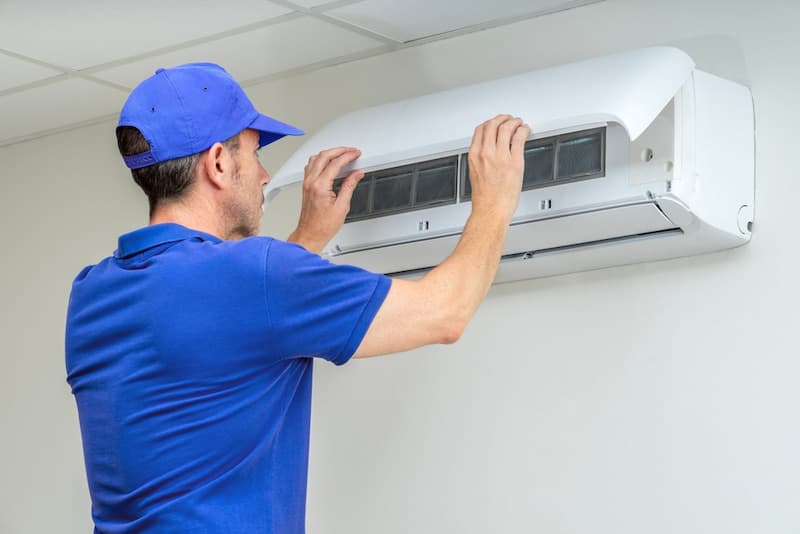 Profissional fazendo a manutenção de um ar-condicionado split na parede